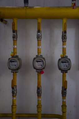 Üst üste birkaç gaz metresi ve içinden sarı demir borular çıkıyor.