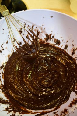 Evde çikolata yapıyorum. Plastik bir kasede sıvı ve koyu çırpma.