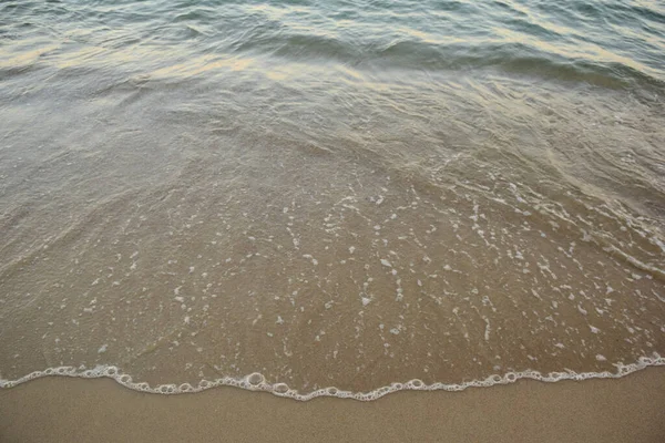 Una pequeña ola marina rueda sobre la playa de arena con agua clara — Foto de Stock