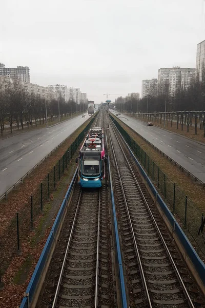Tramway moderne approchant sur un chemin de fer se dirigeant vers la perspective d'une ville nuageuse — Photo