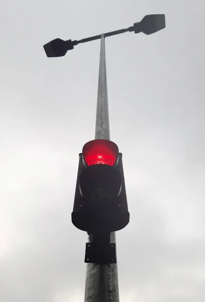 Há um semáforo de duas cores no poste da lâmpada de rua, que é iluminado em vermelho. — Fotografia de Stock