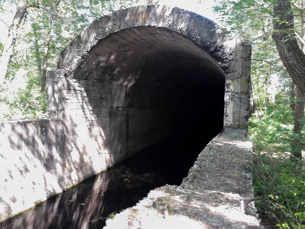 Um fluxo de água flui de um antigo bunker subterrâneo — Fotografia de Stock