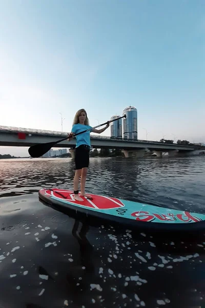一个有运动能力的女孩在独立划桨板上游泳 并帮助自己划桨 — 图库照片