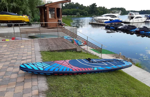 在前景中 一个色彩艳丽的Sup桨停在船坞上 后台的滑板车和汽艇 — 图库照片