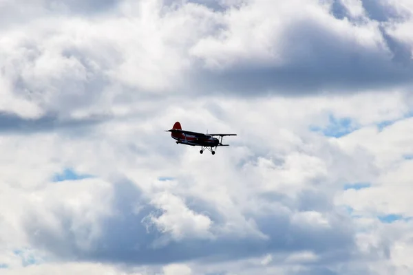 Avión biplano viejo con una hélice vuela en el cielo azul nublado —  Fotos de Stock