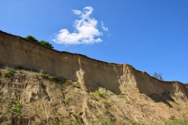 Açık mavi gökyüzüne karşı dik kumlu uçurum