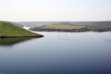 Yeşil tepeler arasındaki geniş bir nehrin kıvrımlı kanalı.