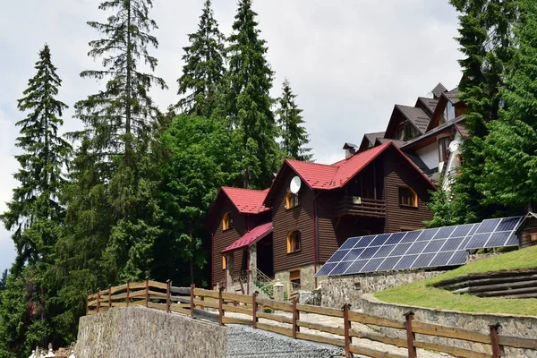 Stugor i fjällskog nära vilka rader av solpaneler för förnybar el — Stockfoto