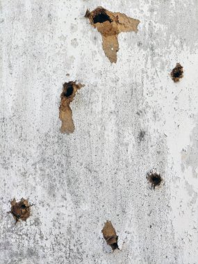 Çerçevedeki ahşap bir kontraplaktaki kurşun deliklerinden geçerek.