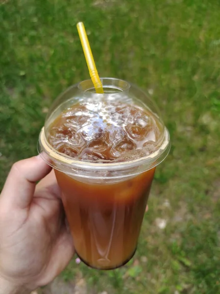 Plastik bardakta, elinde kokteyl tüpü ve kapağı olan bir kokteyl. Arka plan çok bulanık.