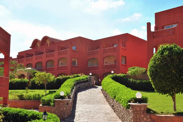 Hotel buildings in oriental style with tiled paths and ornamental trees in the bright sun