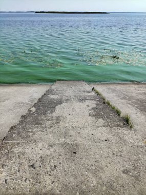 Concrete stairs to a calm wide river in perspective
