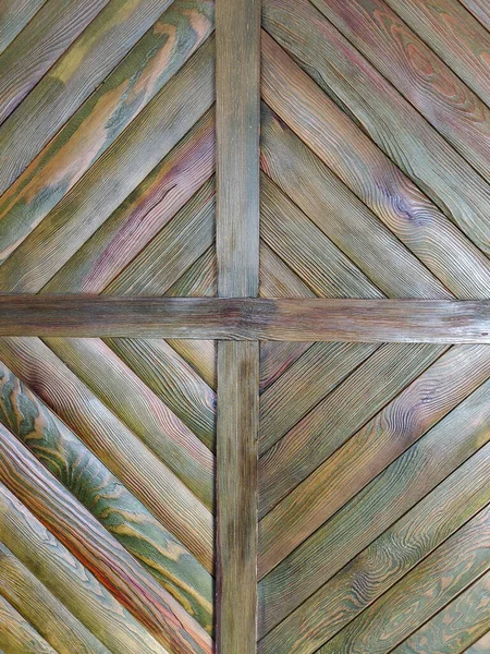 A pattern on the wall made of wooden strips of different shades in the form of a diamond on the entire frame