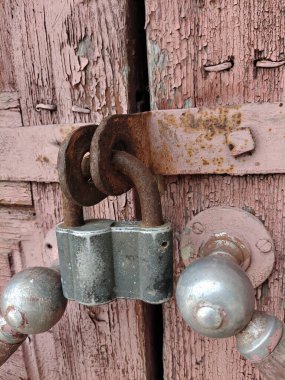 A padlock hangs on the closed door with iron handles of an ancient house. Shot in close-up
