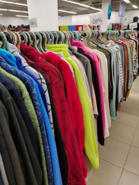 Bir giyim mağazasında değişik renklerde elbise ve gömleklerle sıralanmış askılar ve indirimler.