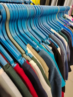 Bir giyim mağazasında değişik renklerde elbise ve gömleklerle sıralanmış askılar ve indirimler.