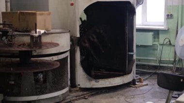 An old furnace for the production of rubber products in a toy factory. The mans hands pull out parts of toys from the press.