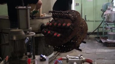 An old furnace for the production of rubber products in a toy factory. The mans hands pull out parts of toys from the press.