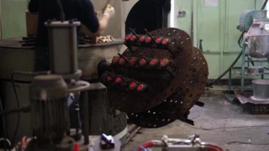 An old furnace for the production of rubber products in a toy factory. The mans hands pull out parts of toys from the press.