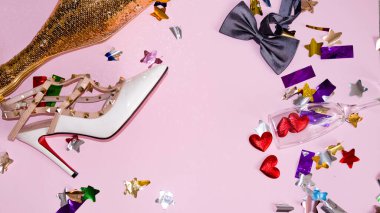 Boş şişeler, bir bardak şarap, kadın ayakkabıları ve pembe bir arka planda papyon olan bir partiyi kutladıktan sonra yukarıdan manzaralı bir resim. Sevgililer Günü 'nü kutluyoruz.