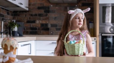 Bandajlı güzel bir çocuk, tavşan kulaklı, renkli yumurtalar sepette, evde, mutfakta. Paskalya için Hazırlık