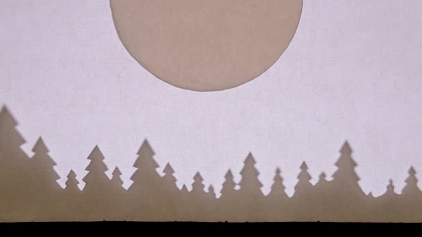 人形の影劇場。トナカイと一緒にそりに乗ってサンタクロースは大きな月の背景に森の上を飛んでいます。上を向いて ストック動画