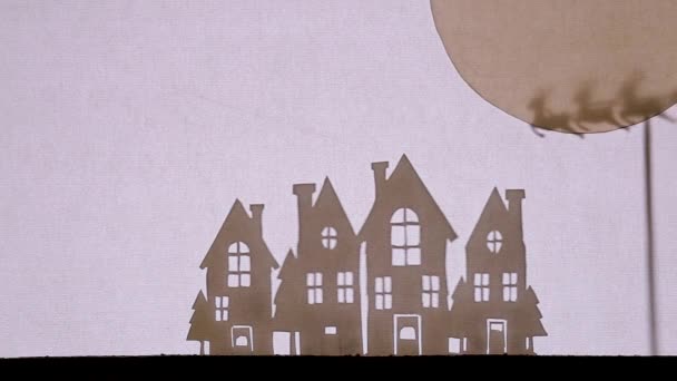 Θέατρο Σκιών Κουκλοθέατρο. Άγιος Βασίλης σε έλκηθρο με μύγες ταράνδων από το μεγάλο φεγγάρι πάνω από σπίτια με λαμπερά παράθυρα — Αρχείο Βίντεο