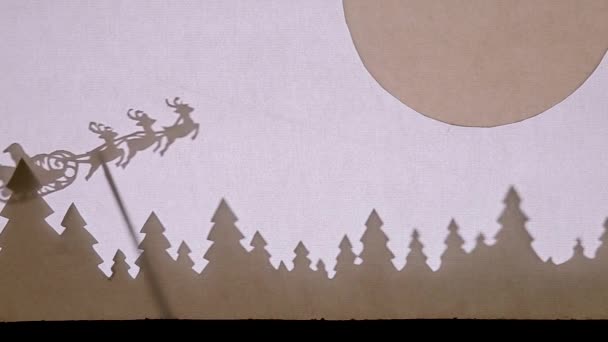 Bábszínház Árnyék Színház. Mikulás egy szánon rénszarvas repül az erdő felett, és repül a nagy hold a jobb sarokban — Stock videók