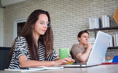 Ev ofisinden ya da ev konseptinden. Genç kadınlar, gençler, evdeki ya da ofisteki masada oturup dizüstü bilgisayarla ya da defterle çalışıyorlar..