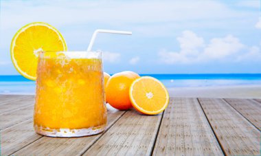 Açık bir bardakta portakal suyu, buz küpleri ve bardağın ağzında portakal suyu. Soğuk içecekler, gün ortasında deniz kenarındaki ahşap balkona konur. 3B görüntüleme
