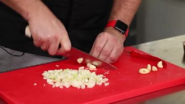 Şef bir bıçak ve kırmızı tabakla suşi kesiyor.