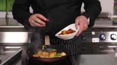 Şef mutfakta yemek pişiriyor.