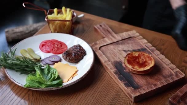 Der Koch Kocht Burger Mit Rindfleisch Und Gemüse Auf Holzbrett — Stockvideo