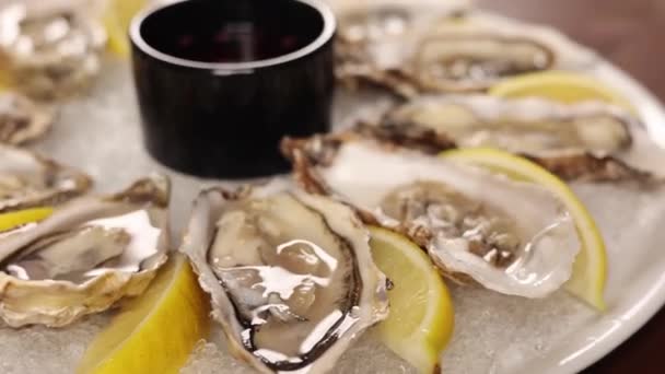 新鲜的牡蛎 盘子里有柠檬和冰块 — 图库视频影像