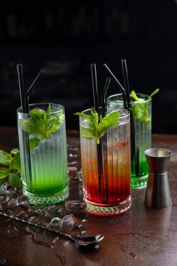 Koyu arkaplanda yeşil limonlu ve naneli kokteyl.