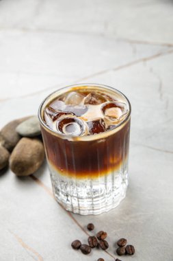 Tahta zemin üzerinde buz küpleri olan bir bardak soğuk kahve.