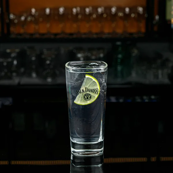 a glass of whiskey with ice and lemon on a bar counter