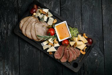 Tahta masanın üzerinde değişik peynirler var.