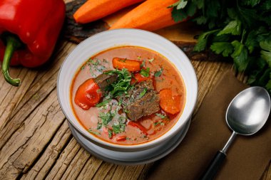 Ahşap arka planda sebzeli ve baharatlı domates çorbası.