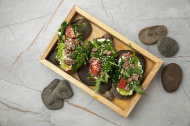 Peynirli bruschettalar, ton balığı, domates, roka ve susam.