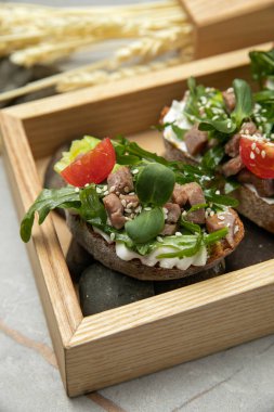 Peynirli bruschettalar, ton balığı, domates, roka ve susam.