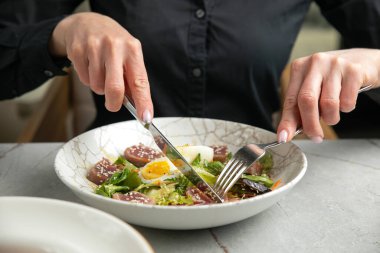 Ton balıklı salata, marul, otlar, yumurta, gri bir masada.