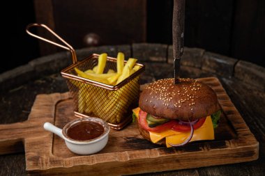 Biftek, peynir, marul, soğan ve salata ile ahşap arka planda ev yapımı hamburger.