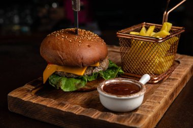 Biftek, peynir, marul, soğan ve salata ile ahşap arka planda ev yapımı hamburger.