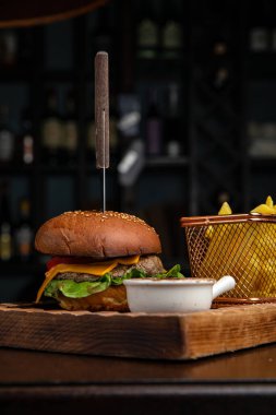 Biftek, peynir, marul, soğan ve salata ile ahşap arka planda ev yapımı hamburger.