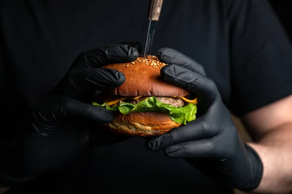 Biftek, peynir, marul, soğan ve salata ile ahşap arka planda ev yapımı hamburger.