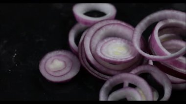 Siyah arkaplanda kırmızı soğan halkaları ve soğanlar, yakın plan.