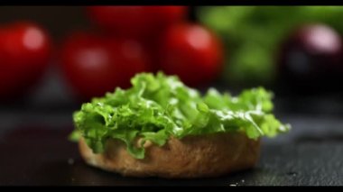 Peynirli hamburger ve siyah arka planda sebze..