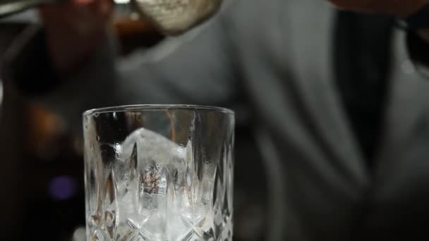 调酒师把鸡尾酒倒入背景模糊的杯子里 — 图库视频影像