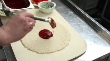 Şef sosisli ve peynirli pizza hazırlar. 